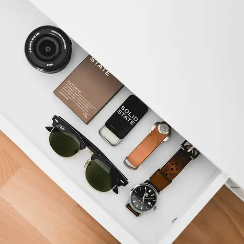Phones, a camera and sunglasses laid out in a drawer