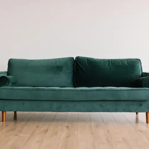 A green velvet sofa on a wood floor