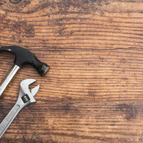 A hammer and a wrench on a wooden board