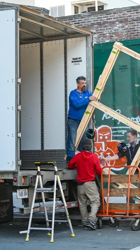 Two workers loading a truck on a city street
