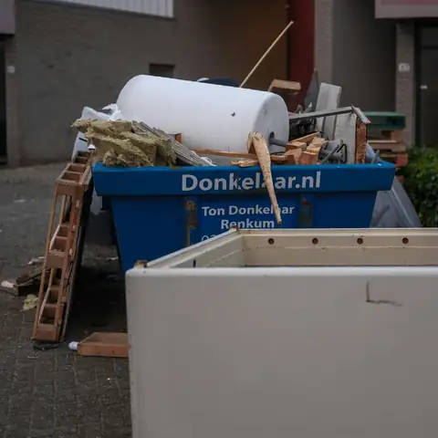 A skip filled with discarded items and an old bathtub