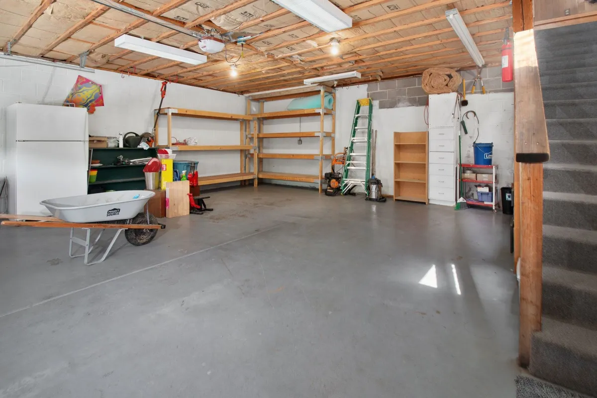 A spacious garage with organized storage shelves, tools, and a wheelbarrow, reflecting effective home organization.